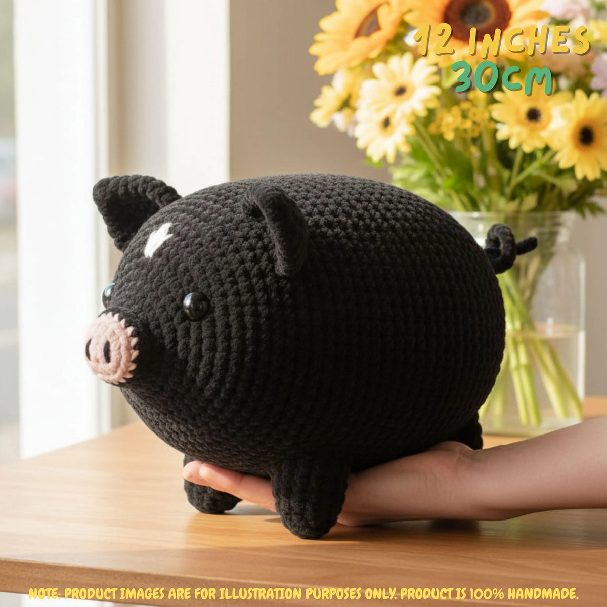A black crocheted pig plush toy being held on a wooden table, with a vase of yellow flowers in the background and text overlays indicating its size is 42 inches (107 cm) by 12 inches (30 cm).