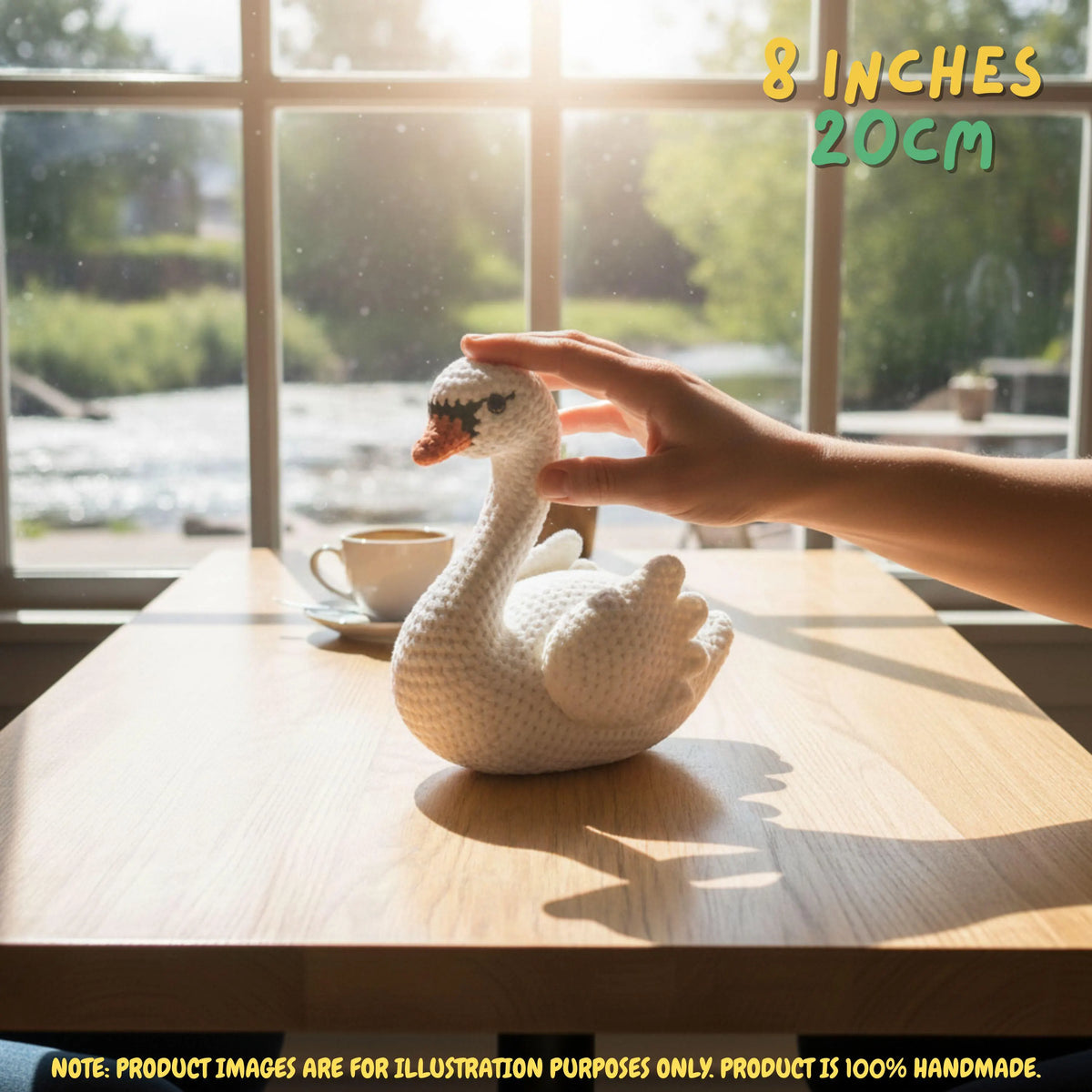 Handmade Mute Swan crochet amigurumi plush doll resting on a wooden table near a window, with a hand gently touching its head.