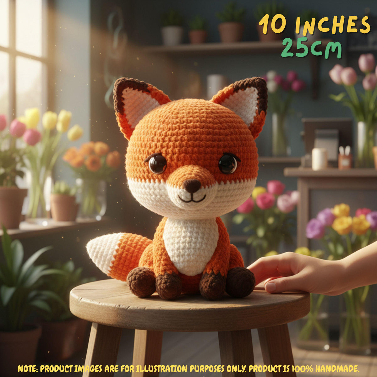 A crocheted fox toy sits on a wooden stool in a cozy, softly blurred room with flowers and shelves in the background. A human hand is touching the tail of the toy.