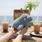 A crocheted seal plush toy held by two hands over a wooden table with bubble tea cups, set against an ocean background with a palm tree and a 'Bubble Tea' sign. Text overlays indicate the size is 8 inches (20cm) and note the product is 100% handmade.