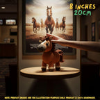 A crocheted horse toy stands on a small round table in a dim indoor setting, with a human arm reaching toward it. A framed poster of running horses hangs on the wall behind, and text in the top right reads 8 inches / 20 cm.