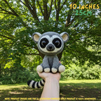 A crocheted raccoon plush toy held up by a person's hand outdoors in front of a leafy green tree. Text in the top right reads '10 INCHES 25CM', and a note at the bottom says product images are for illustration purposes only, with the product being 100% handmade.