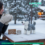 A crocheted husky toy sits on a snow-covered picnic table outdoors in winter, next to a person holding a mug. Text overlays indicate the size as 6 inches (16 cm), with a note stating the product image is for illustration purposes only.
