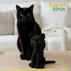 A black crocheted cat doll sits on a light wood table in front of a real living-room setting with a black cat and a white sofa. Text in the top right says '8 INCHES 20CM'.