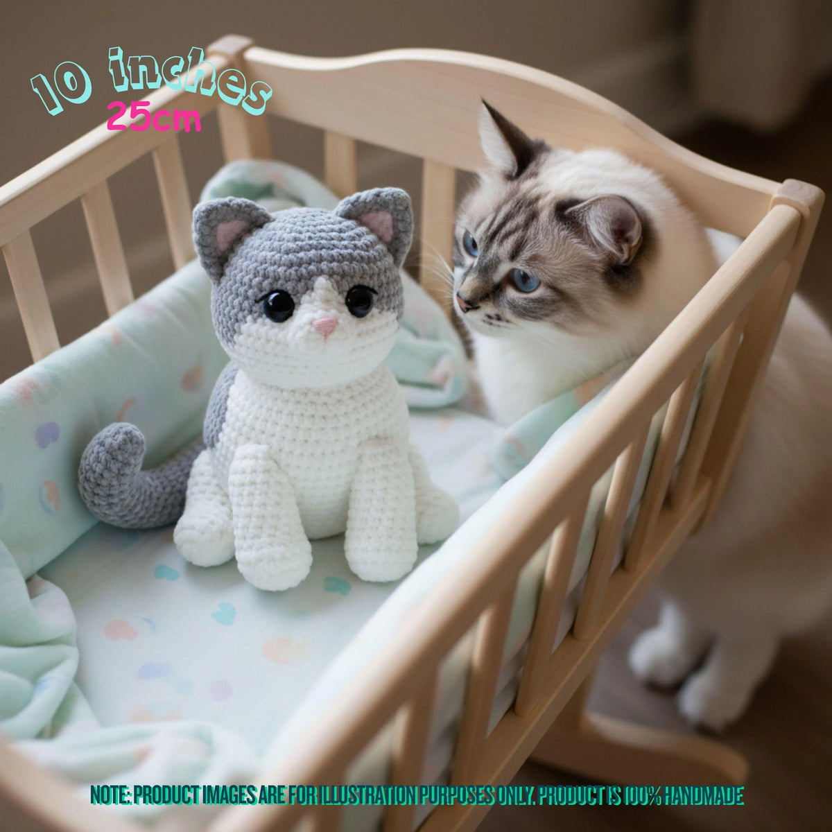 A crocheted plush cat toy sits inside a wooden baby crib next to a real fluffy cat. The toy is gray and white with black eyes and a small pink nose.
