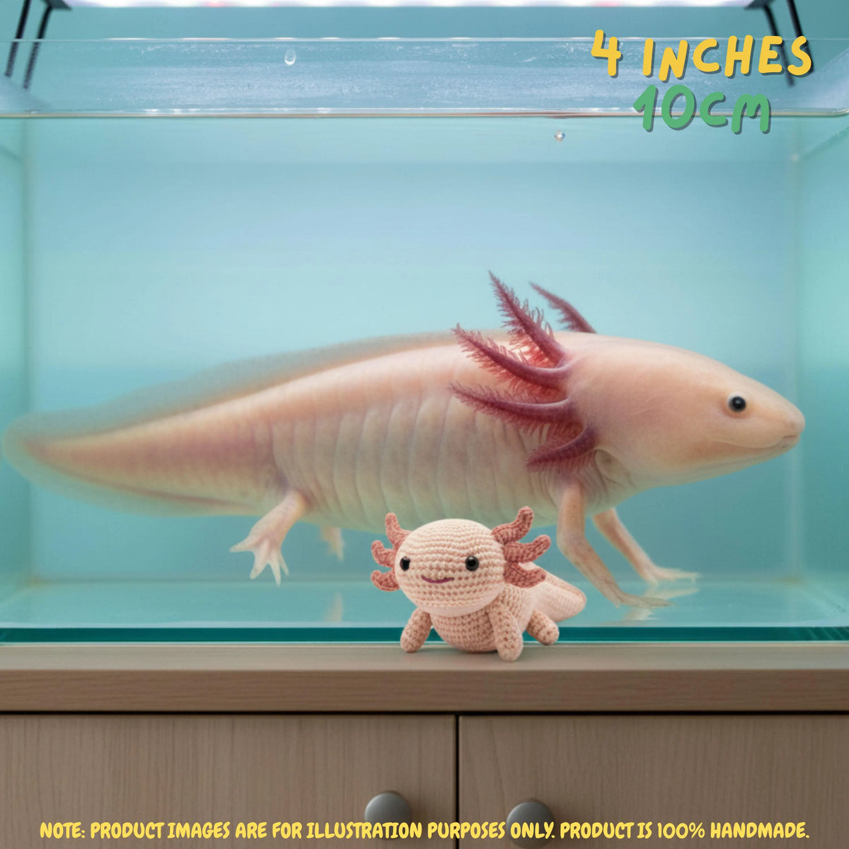 A small crocheted axolotl toy placed in front of a real axolotl in a glass aquarium, with text reading '4 INCHES 10CM' and a note saying product images are for illustration purposes only.