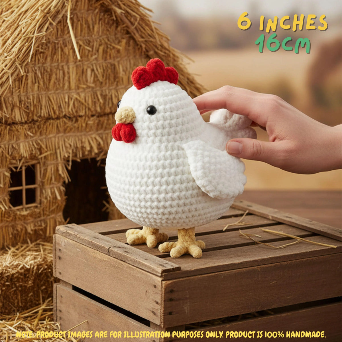 A white crocheted chicken toy with a red comb and yellow beak and feet, shown with a human hand touching it. The toy stands on a wooden crate in front of a straw henhouse, with text reading '6 INCHES 15CM' in the top right.