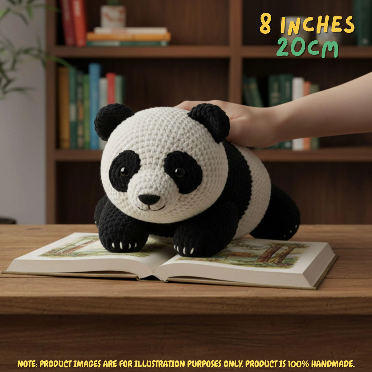 Hand gently resting on top of a handmade giant panda bear crochet amigurumi plush doll lying on an open book on a wooden table in front of a bookshelf, with text reading 8 INCHES 20cm.