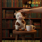 Crocheted cow amigurumi toy sitting on a wooden stool next to a white coffee mug, with a human hand gently touching its head. The background is a cozy bookshelf filled with books, and text overlays indicate the size as 8 inches (20cm) with a note that product images are for illustration purposes only.