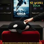 A crocheted orca plush toy resting on a red chair, with a human hand touching its back. A movie poster for 'Orca: The Untitled Ocean' is visible in the background, and text in the top right reads '12 INCHES 30CM'.