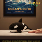 A crocheted orca plush toy resting on a tabletop, with a human hand beside it and a framed ocean-themed print in the background. Text in the top right reads '8 INCHES 20cm' and a note at the bottom says product images are for illustration purposes only.