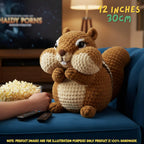A crocheted squirrel plush toy sits on a blue couch in a living room setting, with a hand holding a bowl of popcorn nearby. The text '12 INCHES 30CM' appears in the top right, and a note at the bottom clarifies that product images are for illustration purposes only.