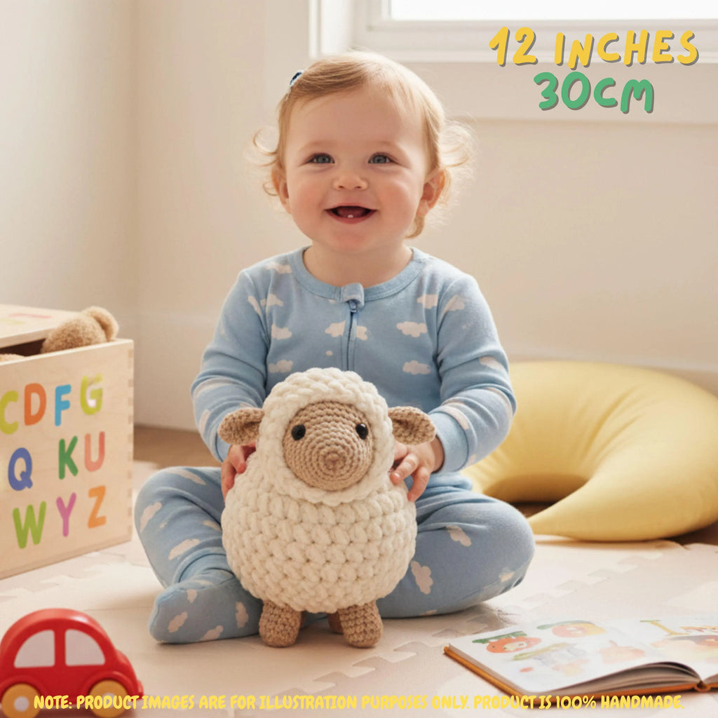 A smiling toddler in a light blue cloud-print pajama set sits on a play mat holding a crocheted sheep toy. The scene includes a wooden alphabet box, a yellow crescent pillow, and text overlays reading '12 INCHES 30CM' and a product note at the bottom.