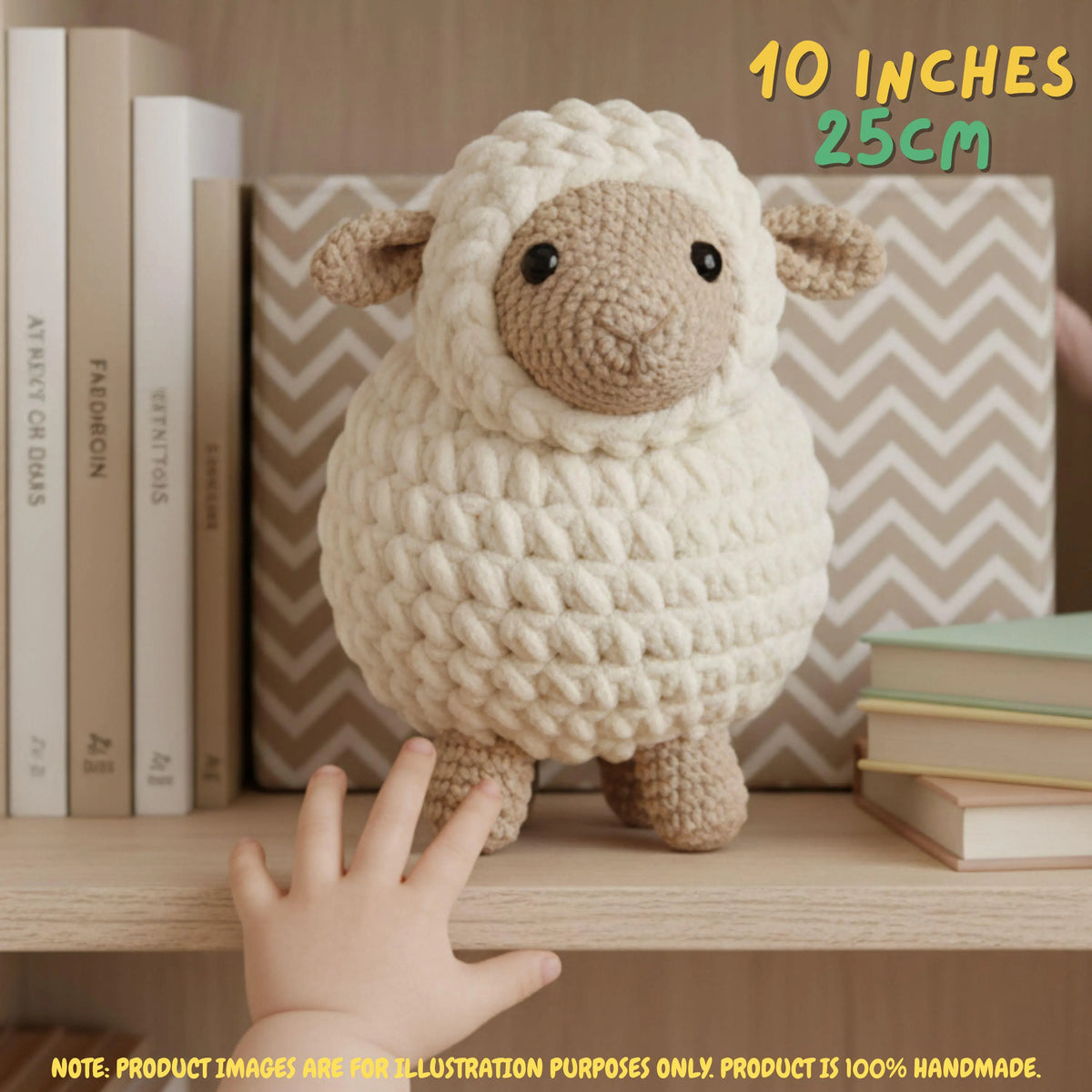 A crocheted plush sheep toy with a cream-colored textured body, tan face and legs, and small black eyes, displayed on a wooden shelf next to books. A human hand is touching the bottom of the toy, and text overlays indicate its size as 10 inches (25 cm) with a note at the bottom stating the product image is for illustration purposes only.