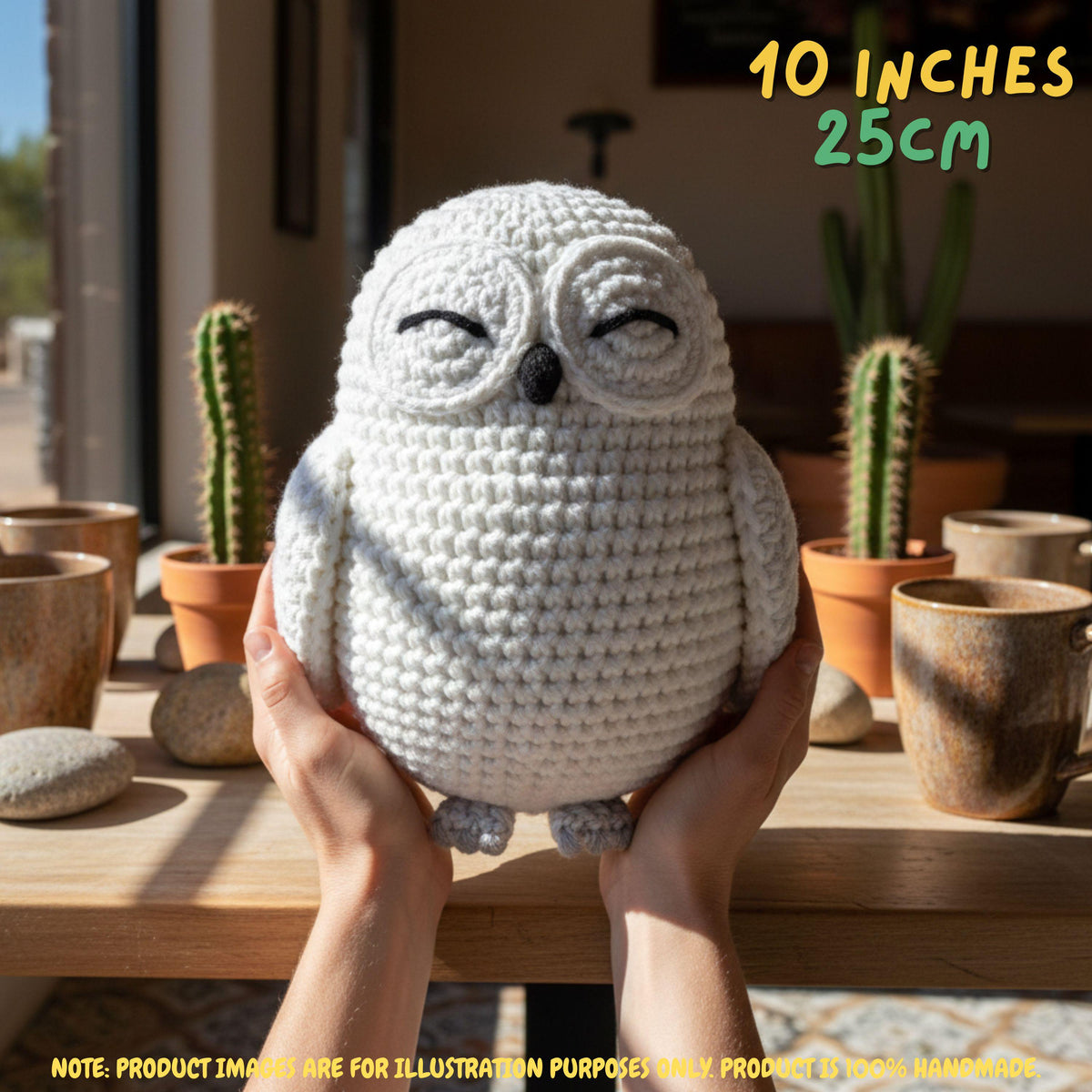 A crocheted owl plush toy being held in two hands, with the text '10 INCHES 25CM' in the top right and a note at the bottom. The owl is off-white with black embroidered eyes and a small black beak.