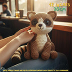 Handmade Ringtail crochet amigurumi plush doll with a striped tail held gently by hands on a wooden table, with text indicating 12 inches 30 cm size in a train car setting.