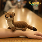 Handmade Stoat crochet amigurumi plush doll in brown and cream with a dark-tipped tail held in a hand on a wooden table, with text indicating 12 inches 30 cm size.