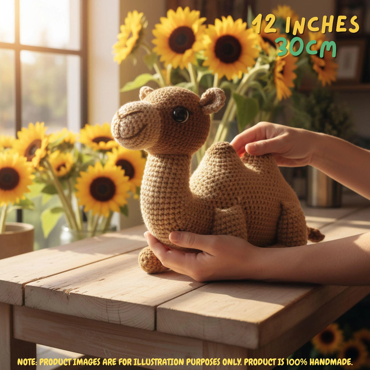 A crocheted camel toy sits on a wooden table, with two hands holding it for scale. Bright sunflowers and warm sunlight fill the background.