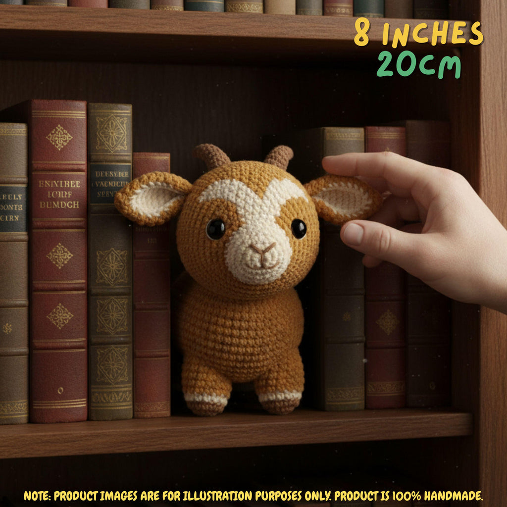 A crocheted small goat toy is displayed on a wooden bookshelf between vintage books, with a human hand touching its ear. Text in the top right says 8 inches / 20 cm, and a note at the bottom says product images are for illustration purposes only.