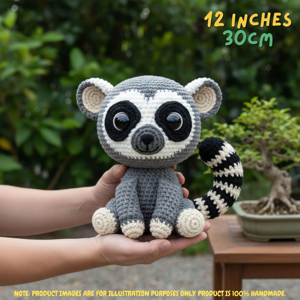 A crocheted raccoon amigurumi toy being held in two hands, with a blurred garden and bonsai tree in the background. Yellow text in the top right reads '12 INCHES 30CM', and a note at the bottom says product images are for illustration purposes only.