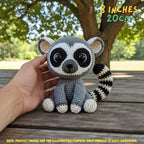 A crocheted raccoon toy being held by a human hand outdoors on a wooden bench, with trees in the background. Text in the top right says '8 INCHES 20CM', and a note at the bottom says product images are for illustration purposes only.