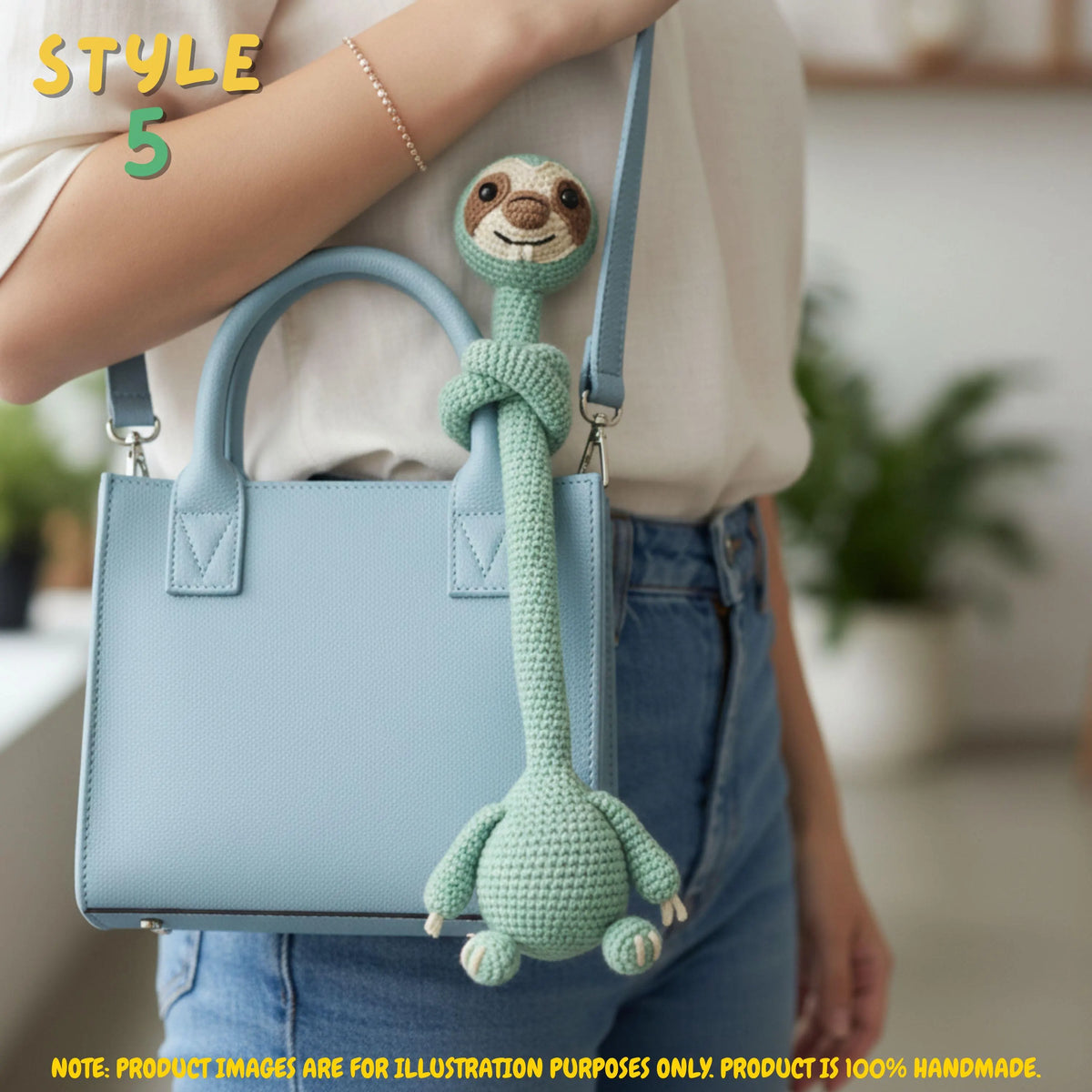 Handmade green crochet long-neck sloth bag charm with "STYLE 5" text overlay wrapped around the strap of a light blue handbag worn by a person.
