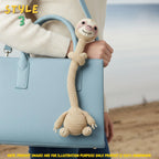 Handmade beige crochet long-neck sloth bag charm with "STYLE 3" text overlay attached to a light blue leather shoulder bag.