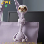 Handmade purple crochet long-neck sloth bag charm with "STYLE 6" text overlay wrapped around the handle of a matching purple tote bag.