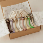 Handmade beige crochet long-neck sloth bag charm with "STYLE 7" text overlay wrapped around the handle of a dark brown leather handbag.