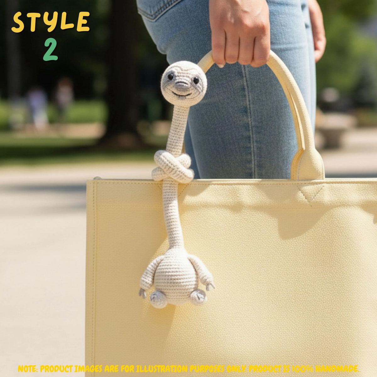 Handmade beige crochet long-neck sloth bag charm with "STYLE 2" text overlay attached to a pastel yellow tote bag.