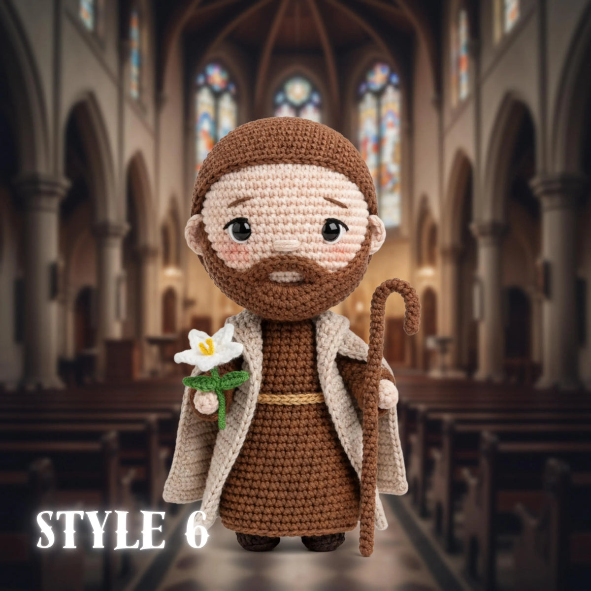 A crocheted amigurumi figure of a bearded man in brown robes and a cream coat, holding a white flower and a staff, standing in front of a blurred cathedral interior. The text 'STYLE 6' appears in the lower left corner.