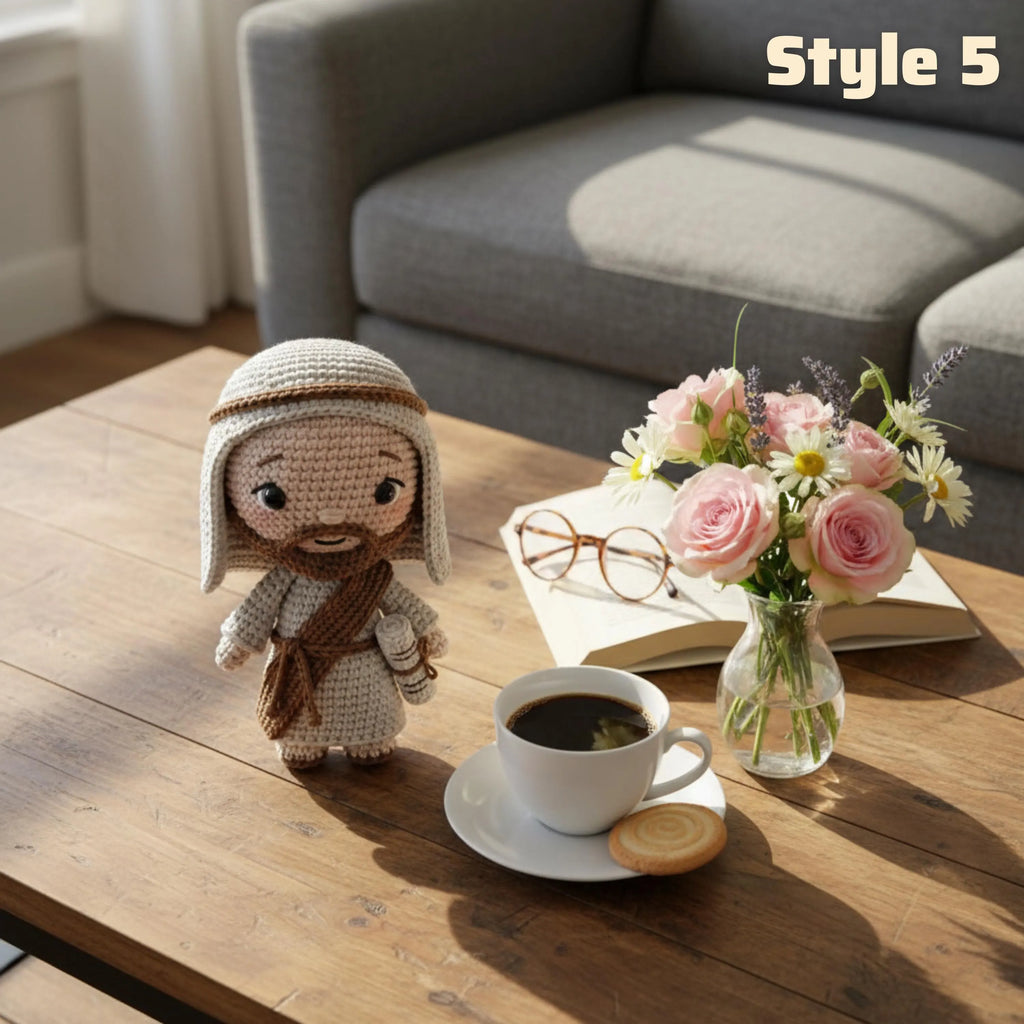 A crocheted doll dressed in a beige and brown robe stands on a wooden coffee table beside a cup of coffee, an open book with glasses, and a small vase of pink flowers. A gray sofa is visible in the background, and the text 'Style 5' appears in the top right.