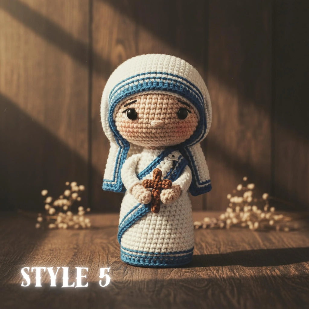 A crocheted doll styled like the Virgin Mary stands on a wooden surface against a dark wood plank background. The doll is cream-colored with blue trim and holds a brown cross.