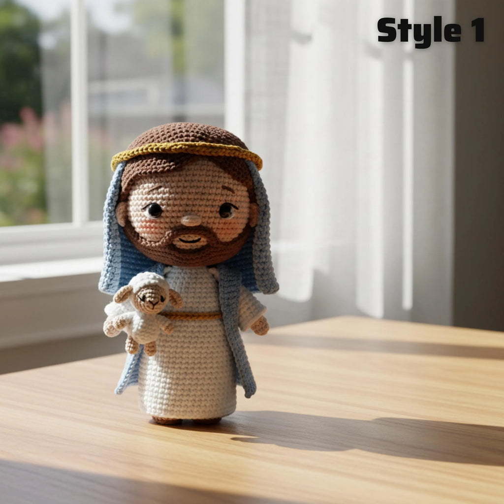 A crocheted doll of Jesus holding a lamb stands on a wooden table in a sunlit room. The doll has brown hair and beard, a white robe, a blue drape, and a gold headband.