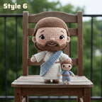 Crocheted Jesus and child doll set styled on a wooden chair with a blurred outdoor garden background. The larger doll represents Jesus with brown hair and beard, white robe, and blue sash, while the smaller doll represents the child.