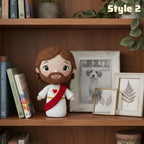 A crocheted plush doll with brown hair and beard, wearing a white robe and red sash, displayed on a wooden bookshelf next to picture frames and books. The text 'Style 2' appears in the top right corner.