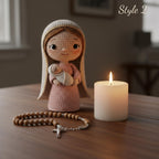 A crocheted doll wearing a beige veil and holding a swaddled baby figure stands on a wooden table beside a lit white candle and a wooden rosary with a silver cross. The background is softly blurred, and the words 'Style 2' appear in the top right.