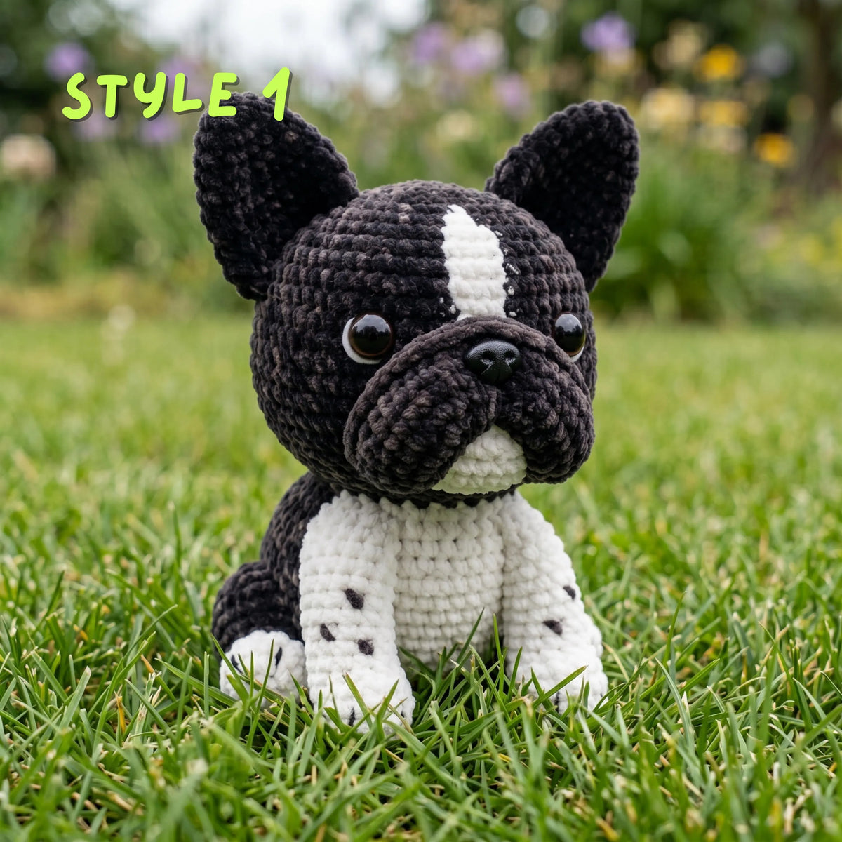 A crocheted dog toy styled like a black and white French bulldog sitting on green grass outdoors, with the text 'STYLE 1' in the top left corner.