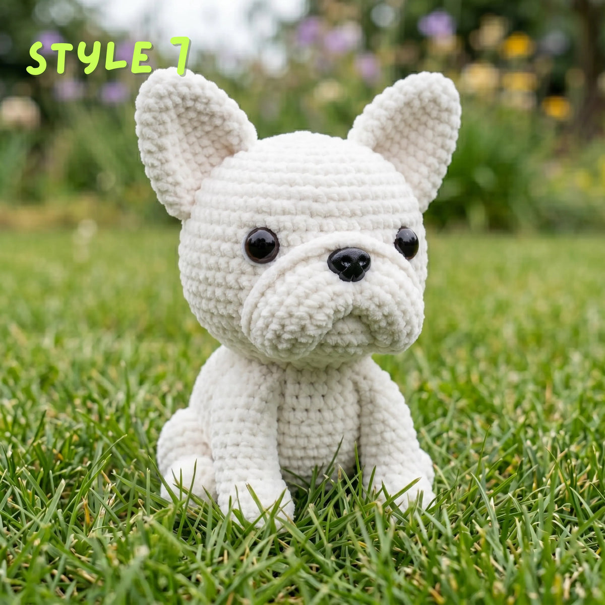 Handmade solid cream white crochet French Bulldog amigurumi plushie with "STYLE 7" text overlay sitting on green grass.