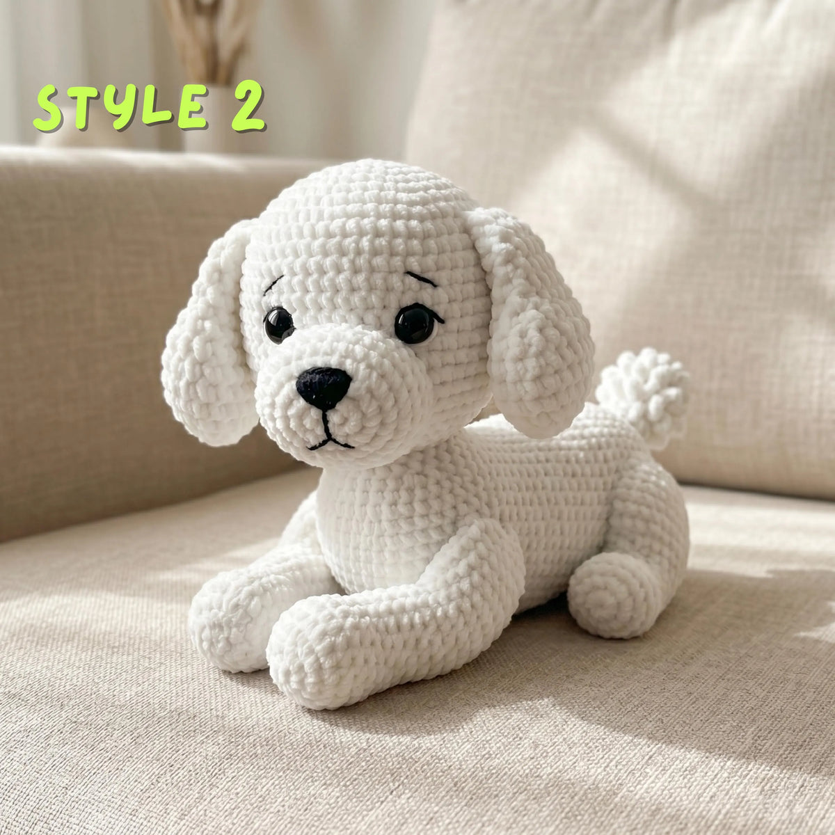 A crocheted white puppy doll with black eyes and nose sits on a beige fabric surface. The text 'STYLE 2' appears in the upper left corner.