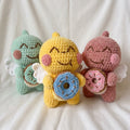 Three colorful crochet toys resembling characters with donut-themed accessories on a white background