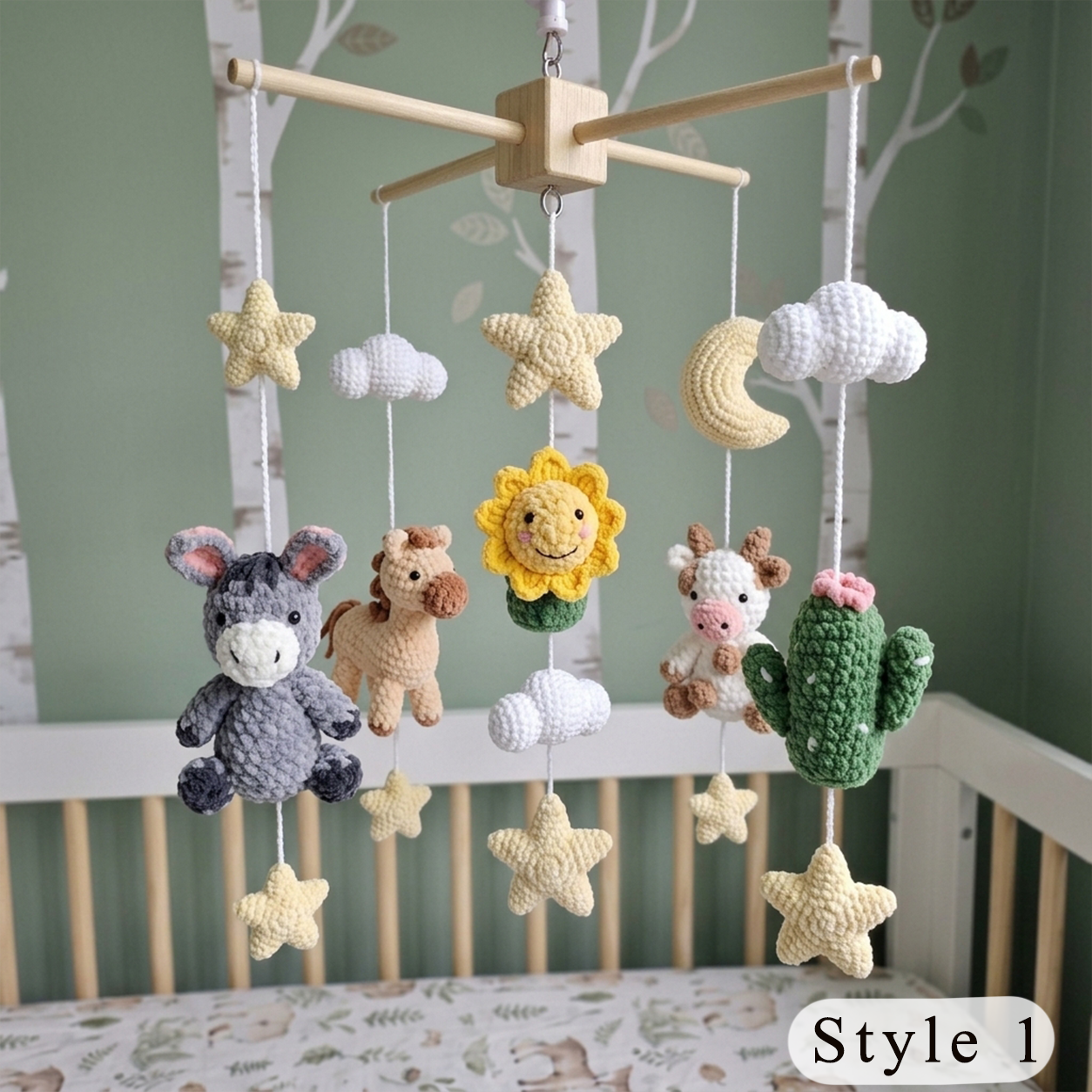 A crocheted baby mobile with animal and nature motifs, hanging in a crib. The mobile features a gray donkey, a brown horse, a yellow sunflower, a white cow, a green cactus, a cream moon, stars, and clouds.