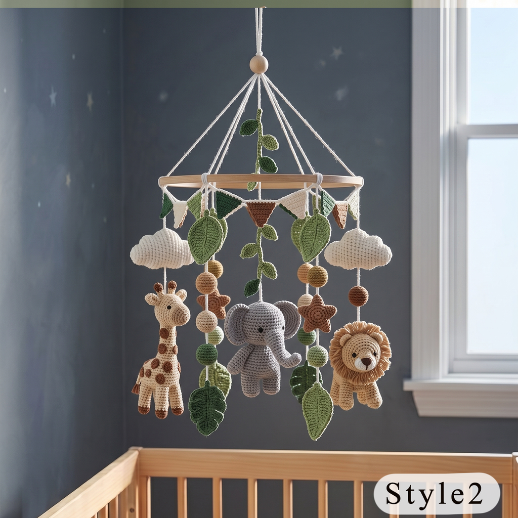 Crocheted baby mobile hanging in a nursery, featuring a giraffe, elephant, lion, clouds, leaves, and wooden beads on a wooden ring, shown above a crib in a gray room.